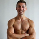 Młody mężczyzna o sportowej sylwetce, uśmiechnięty i pełen optymizmu, symbolizujący osiągnięcie celów fitness.